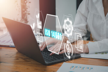 ISO 14001 concept, Business woman using laptop computer on office desk with iso 14001 icon on...