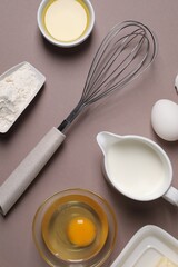 Flat lay composition with whisk and dough ingredients on grey background