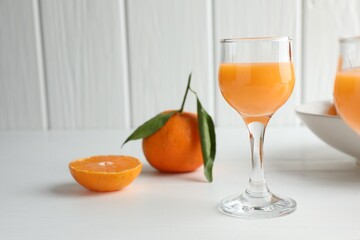 Tasty tangerine liqueur in glass and fresh citrus fruits on white table. Space for text