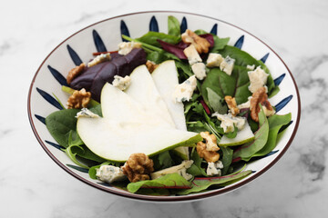 Delicious pear salad in bowl on white marble table, closeup