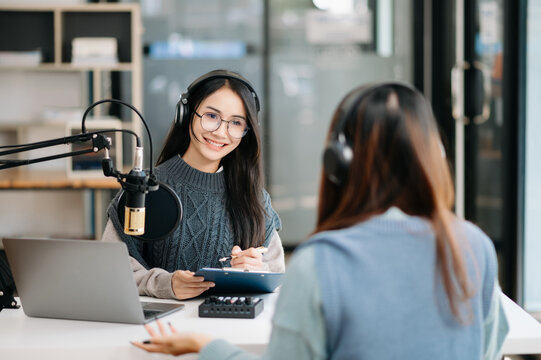 Young woman and Asian woman wearing headphones and doing a live podcast for their channel, communication for radio podcast and technology concept.