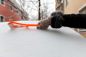 Winter season driving. Close-up of a hand cleaning a vehicle's windshield from ice and snow....