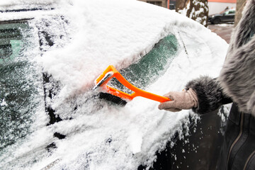 Winter season driving. Close-up of a hand cleaning a vehicle's windshield from ice and snow....