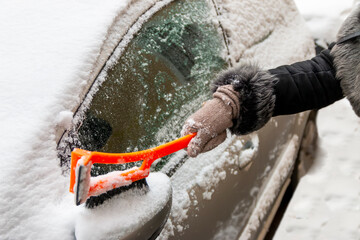 Winter season driving. Close-up of a hand cleaning a vehicle's windshield from ice and snow. Transportation, winter, weather, people and vehicle concept