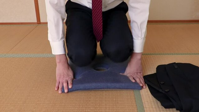 畳の上に上着を置いて座布団に正座で座る男性