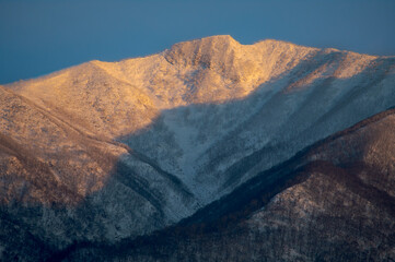 Naklejka premium 朝の太陽に照らされた雪山。