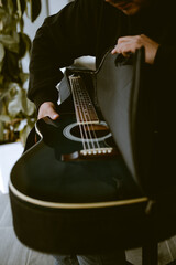 Photograph of a person taking a guitar out of its case. Concept of hobbies.