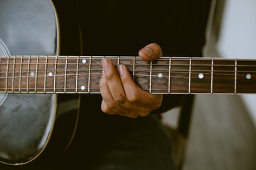 Photo detail of unknown person playing an old acoustic guitar. Concept of hobbies.
