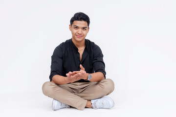 A young southeast asian man sitting indian style, making a proposition. Studio shot isolated on a...