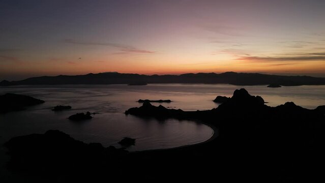 Drone aerial moving forward over islands during sunset showing silhouette landscapes