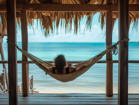 A Photo Of A Solo Traveler Relaxing In A Hammock On The Porch Of A Beach Hut Rental With The Ocean In The Background