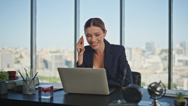 Smiling businesswoman consulting online talking laptop in panoramic office.