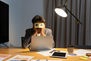 Exhausted young Caucasian man worker have sticker pads on eyes sleeping near computer in office. Tired millennial male employee fall asleep doze off at workplace.