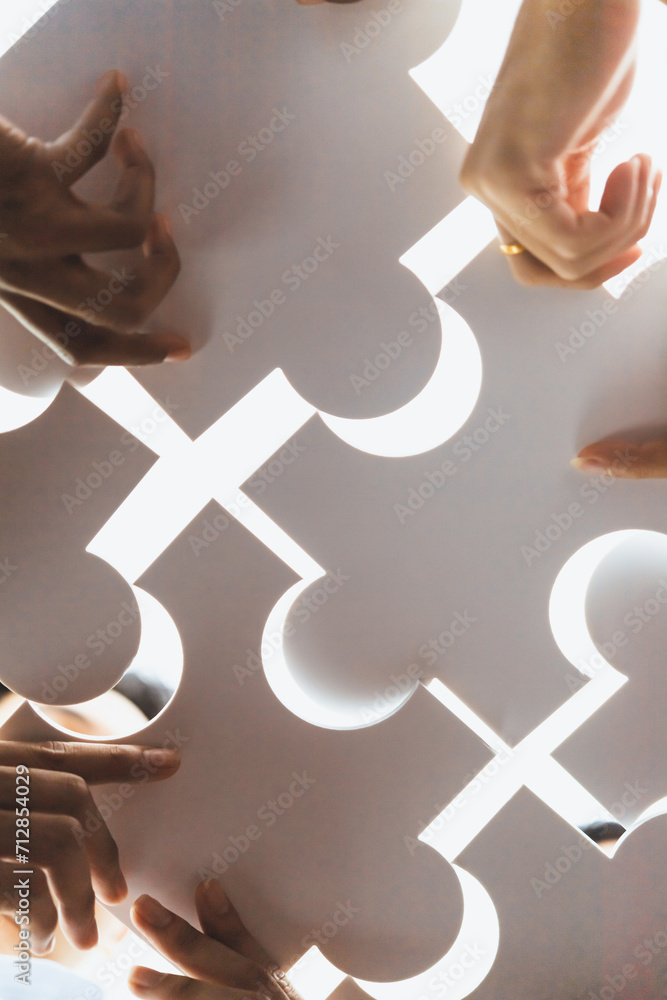 Poster below view of diverse corporate officer workers collaborate in office connecting puzzle pieces as pa