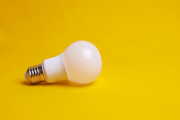 White eco friendly light bulb on yellow background. Energy saving concept by using LED lights