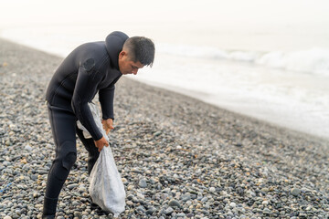 Fisherman wearing wetsuit holding a bag with stones