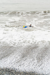 Obraz premium Man in wetsuit swimming on a brave sea