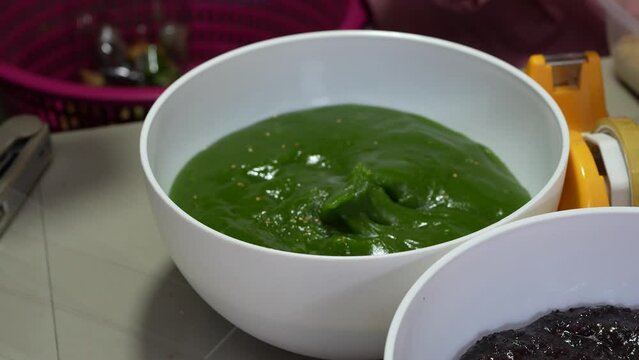 Close-up woman's hand dips into a bowl of green caramel to make a dessert.