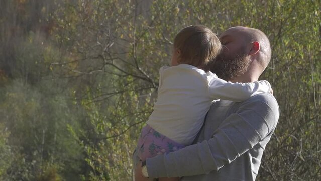 Daddy holding sleepy daughter in his arms gives her a kiss. Fatherhood and parenthood responsibility. Family love. Dad and child spending time bonding playing in park.
