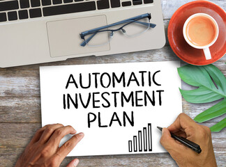 Automatic investment plan letters written on white paper and cup of coffee on wooden tablePersonal...