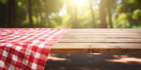 Picnic table with a red checkered towel, empty space, and a blurred wooden deck backdrop. Promotion...