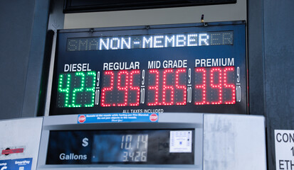 gas pump nozzle with rising numbers on the display, symbolizing inflation and escalating gas prices
