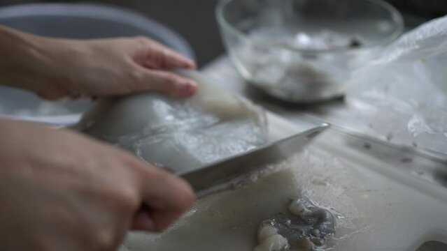 Woman hands knife cut fresh squid cuttlefish cleaning preparing seafood home kitchen