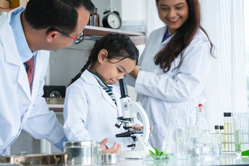 Asian scientist kid student and Indian teacher with plant at biology class in school laboratory, smiling, teaching child girl to use microscope. Education, science and school concept