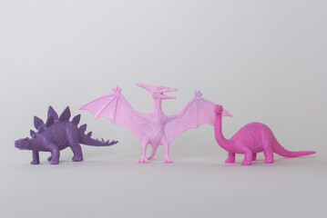 Tree small plastic dinosaur figurine on gray background, little plastic colorful statuettes