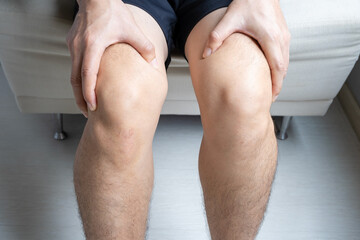 Man with knee pain, he puts his hand on his knee, pain point from osteoarthritis and...