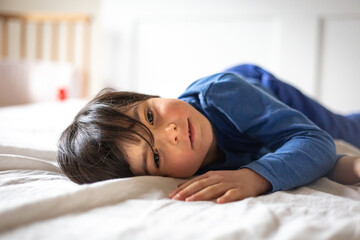 close-up portrait of lying on the bed dark hair child watching aside