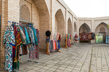 Multicolored national oriental costumes for men and women and carpets on street near souvenir shops