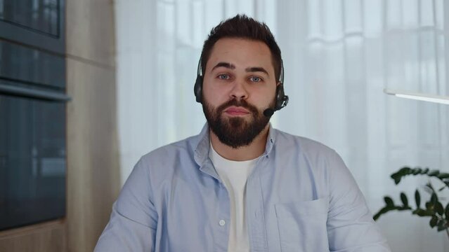 Caucasian man in wireless headset with microphone having video chat with colleagues and looking at camera. Respected boss presenting motivation speech for hired employees and using modern technology.