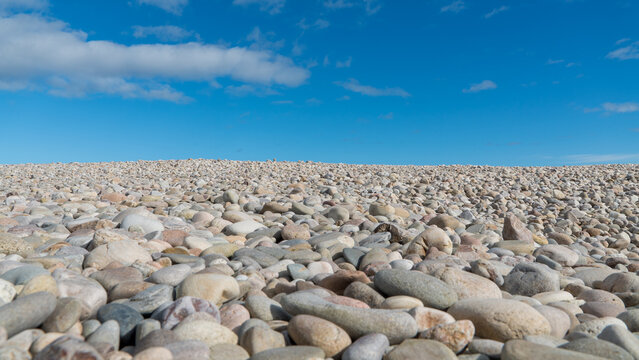 Pebbles on the beach with blue sky and light clouds on the coast of Scotland