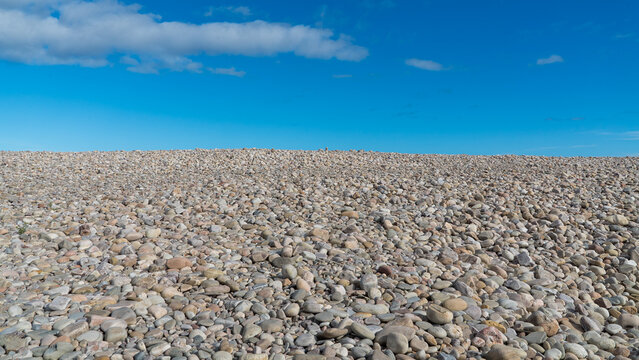 Pebbles on the beach with blue sky and light clouds on the coast of Scotland