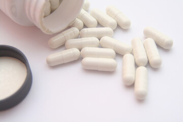 White pills spilling out of pill bottle. Focus on foreground, soft bokeh.