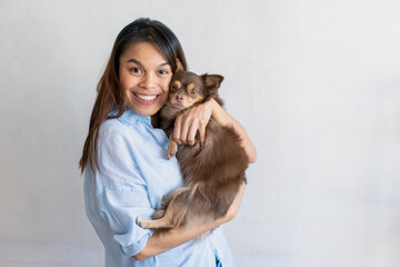 Obraz premium Joyful fit woman sitting having fun with cute dog on the armchair at living room one autumn day , friendship and love for pets.
