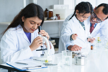 Indian scientist woman student using microscope do an experiment at biology class in school...