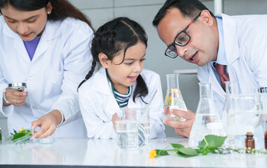 Asian scientist kid student and Indian teacher looking at plant in test tube at biology class in school laboratory, do an experiment, learning, teaching. Education, science and school concept