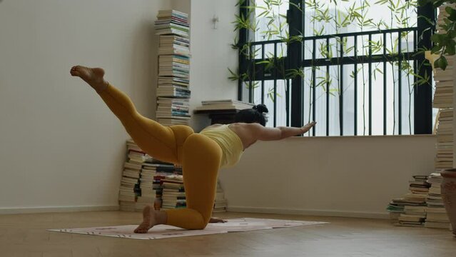 Fit athletic asiatic woman practicing yoga workout routine in modern house apartment