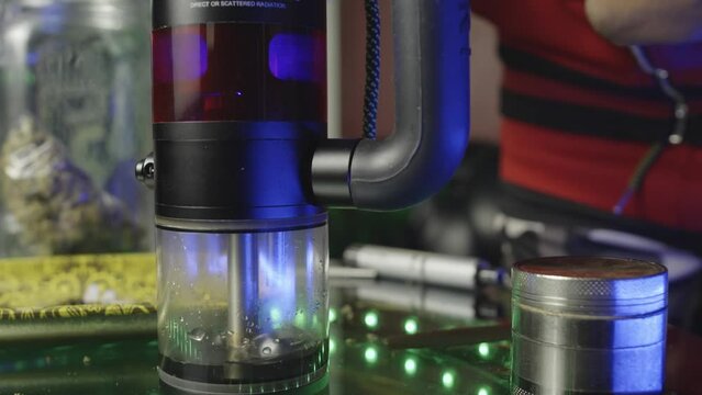close up of the chamber of an electronic water bong as it  bubbles and fills with smoke as someone hits the weed pipe then exhales the smoke from the marijuana