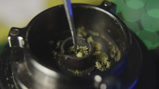 using a stylus to rearrange the  Cannabis bud in  the bowl of an electronic marijuana vaporizer