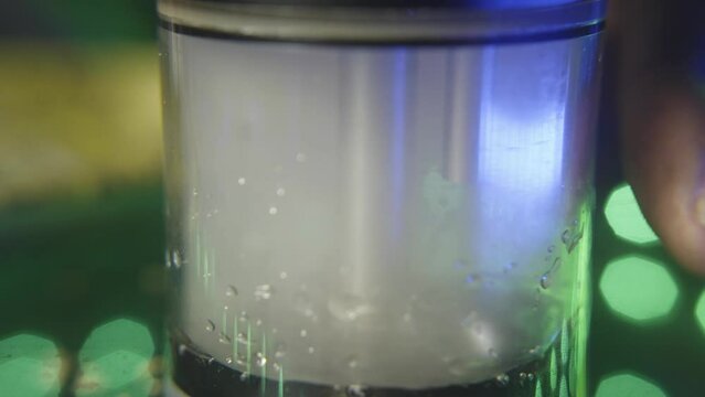 static shot of the chamber of an electronic marijuana water bong. the resin water bubbles as the smoke empties the chamber while someone takes a hit of the weed