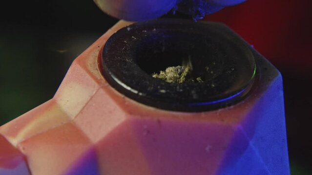 close up shot of breaking up marijuana into a rubber pipe to be smoked