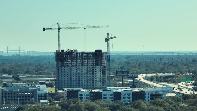 Tower lifting cranes at high residential apartment building construction site. Real estate development