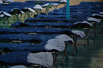 Cots with sleeping bags are placed in the school gym during an emergency