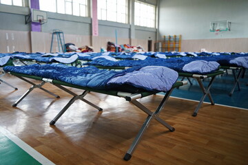 Cots with sleeping bags are placed in the school gym during an emergency