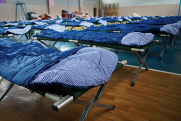Cots with sleeping bags are placed in the school gym during an emergency