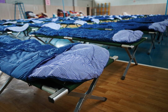 Cots with sleeping bags are placed in the school gym during an emergency