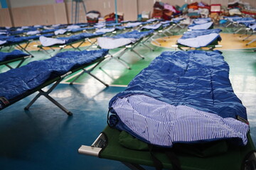Cots with sleeping bags are placed in the school gym during an emergency